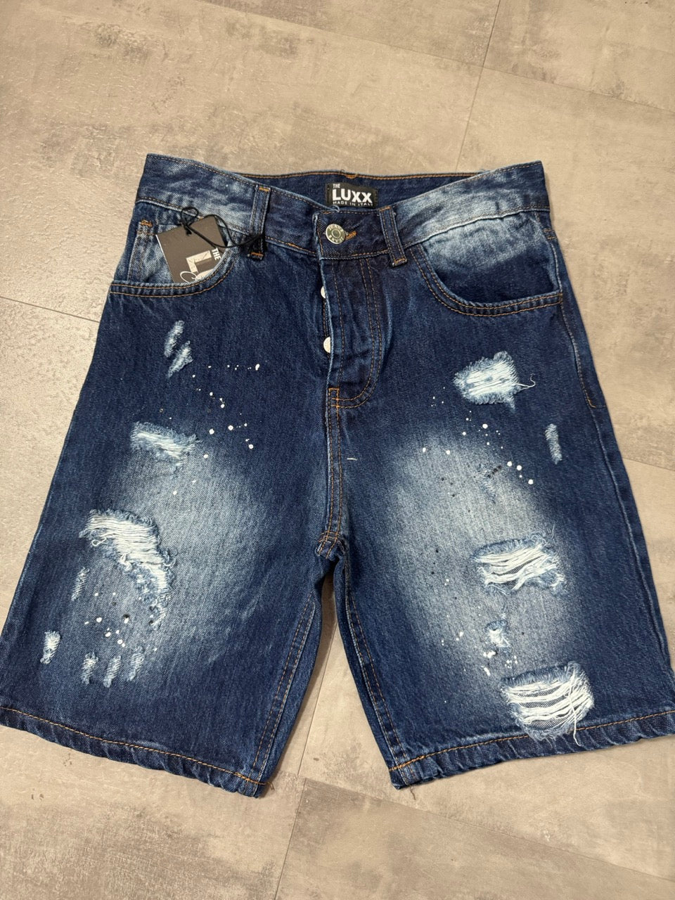 Pantaloncino bermuda blu in denim con strappi e schizzi di vernice
