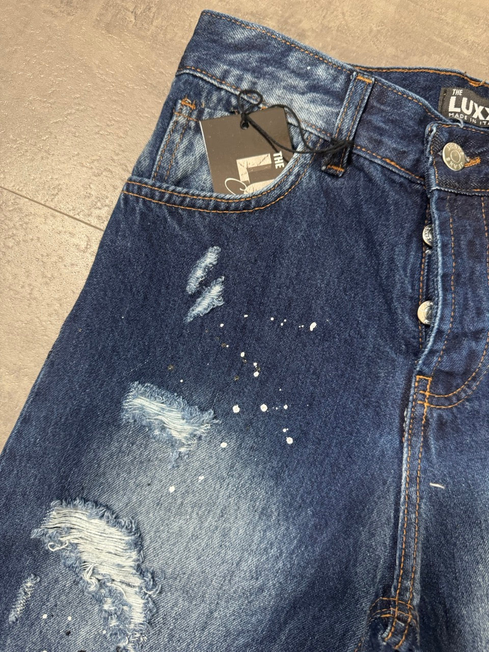 Pantaloncino bermuda blu in denim con strappi e schizzi di vernice